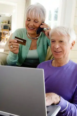 Senior man using laptop computer, senior woman phoning, holding credit card --- Image by © A. Chederros/Onoky/Corbis