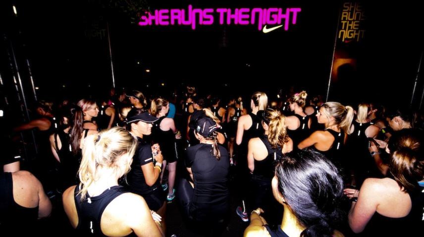 a crowd of women gathering at night to run at Nike's She Runs the Night race