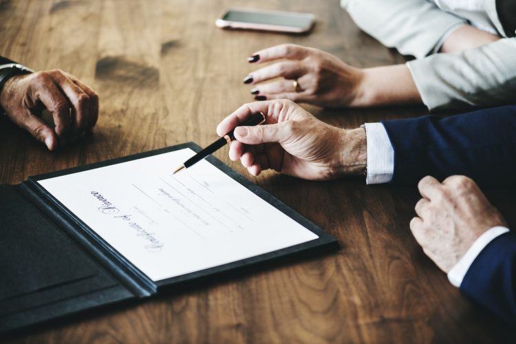 un grupo de personas sentadas a una mesa mirando una tableta con gráficos en la pantalla