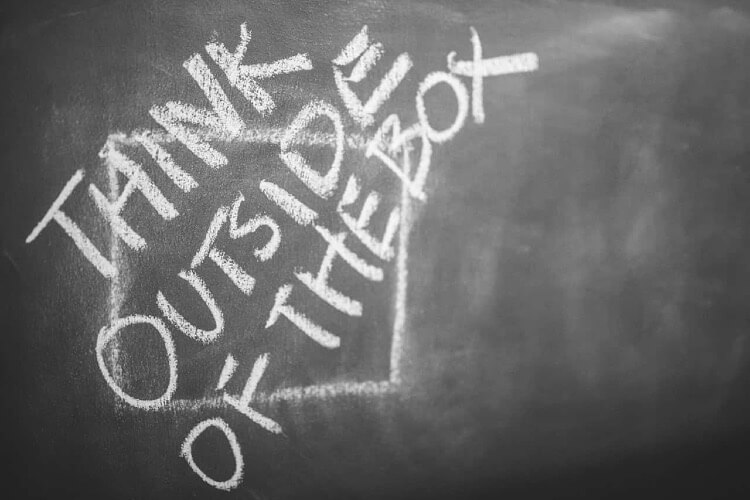 words Think outside the box written with chalk on a blackboard
