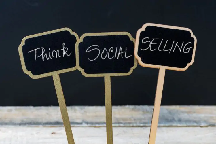 think social selling written with chalk on wooden mini blackboard labels, defocused chalkboard and wood table in background