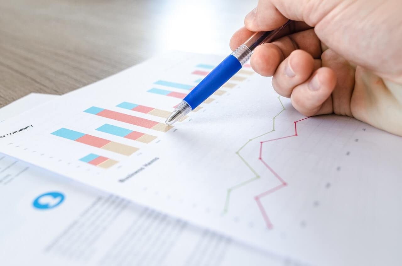 a man holding a pen over prints with graphs and charts