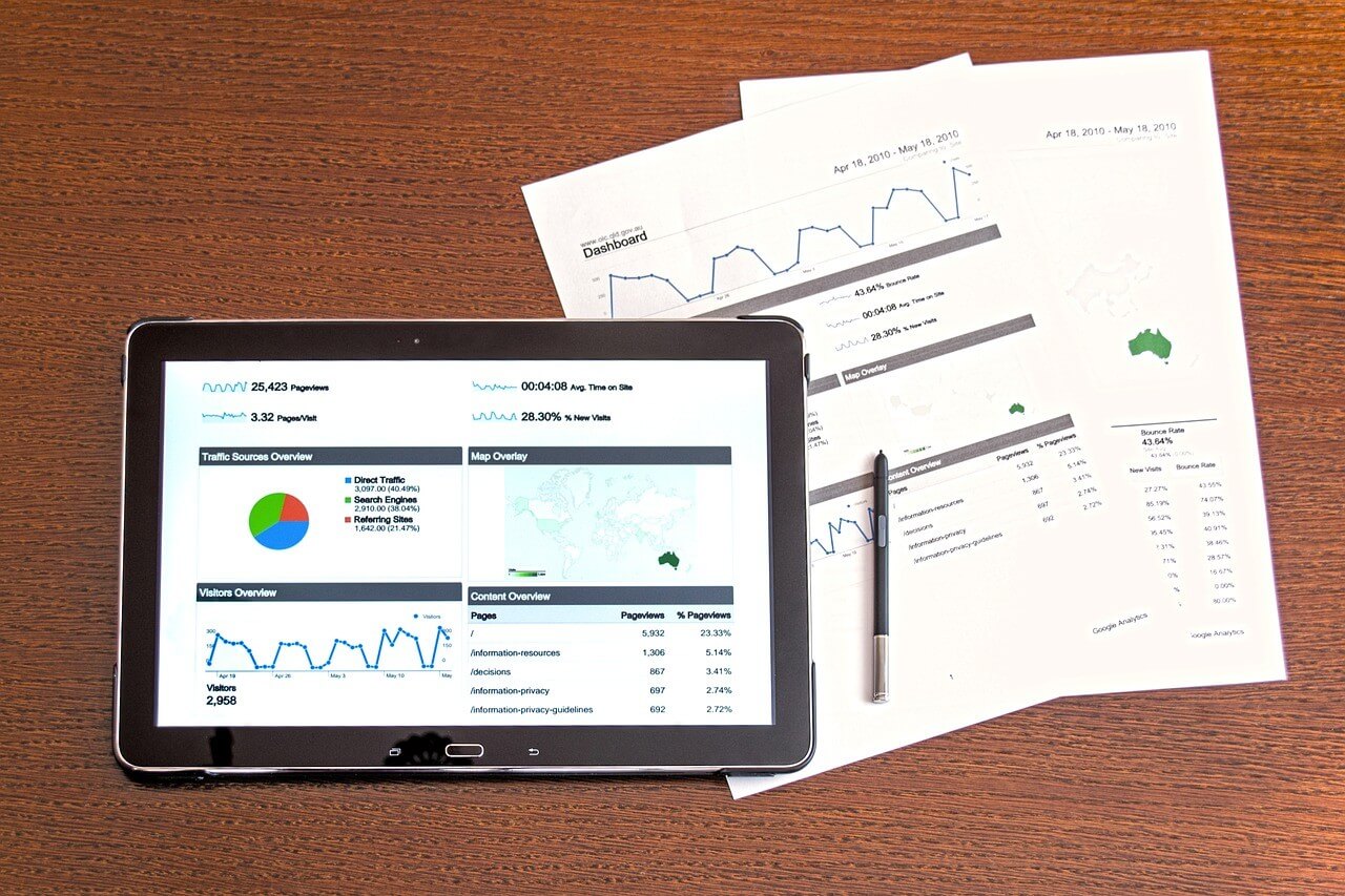 an aerial view of a tablet and print outs with tables on a wooden table