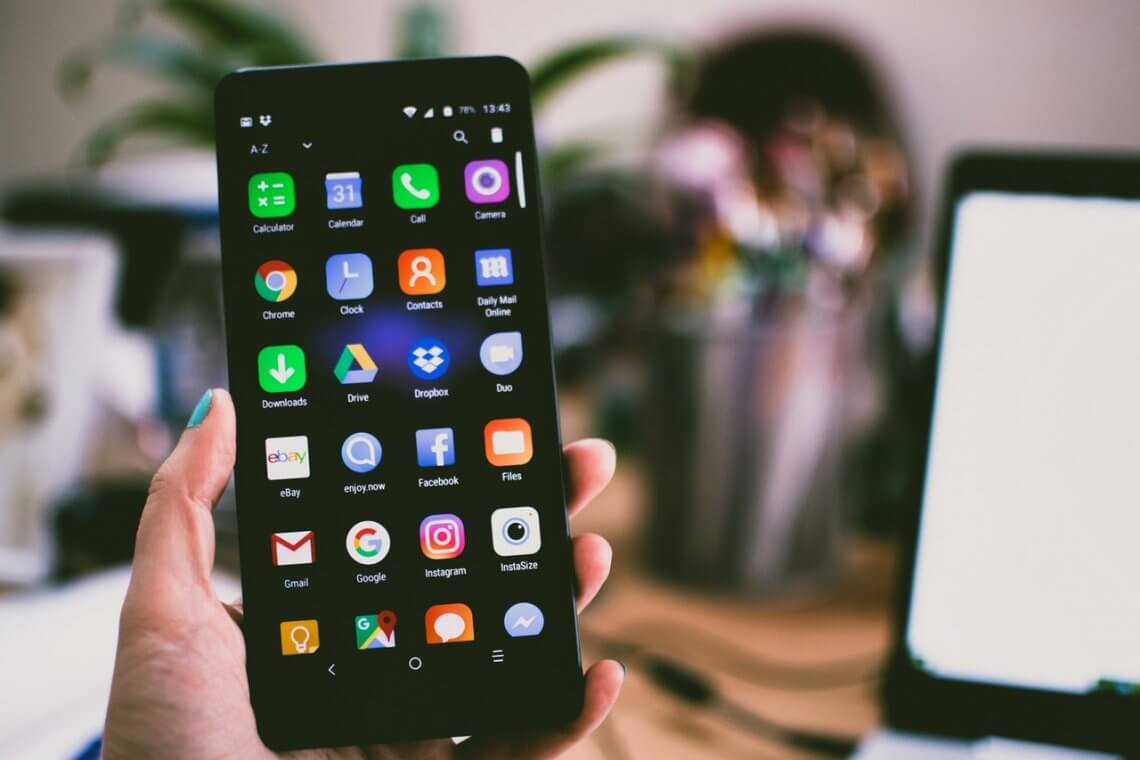 a person holding a smartphone with different apps on the screen