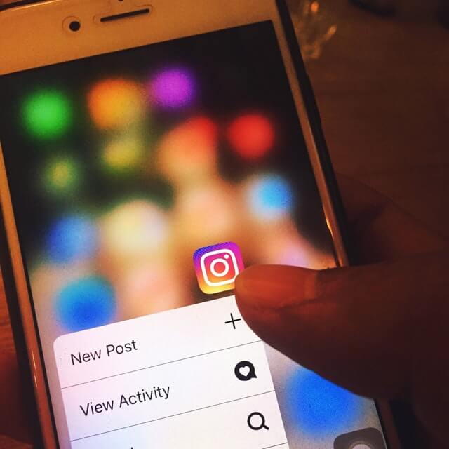a dimmed photo of a smartphone hold by someone with Instagram app open